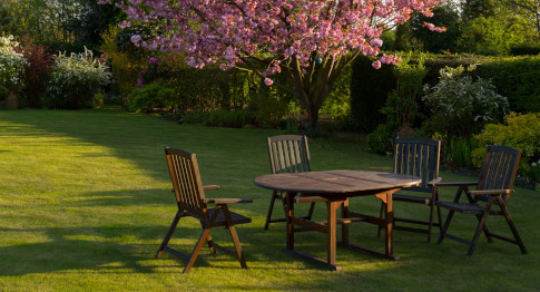 drewniane meble ogrodowe na trawniku, okrągły stół w otoczeniu czterech krzeseł ogrodowych