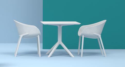 Dwa krzesła przy stoliku z katalogu mebli gastronomicznych stojące na tle zielonej ściany